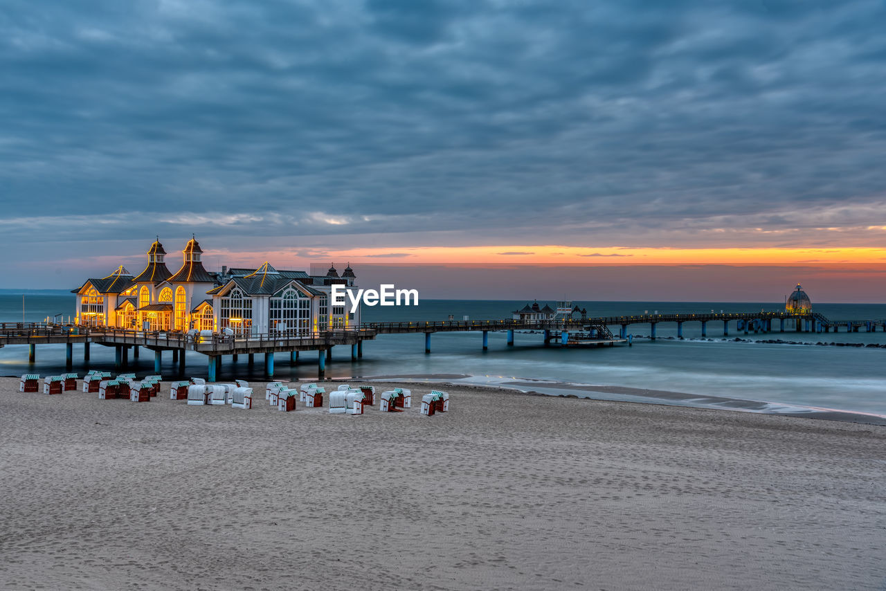 PIER ON BEACH AGAINST SKY AT SUNSET