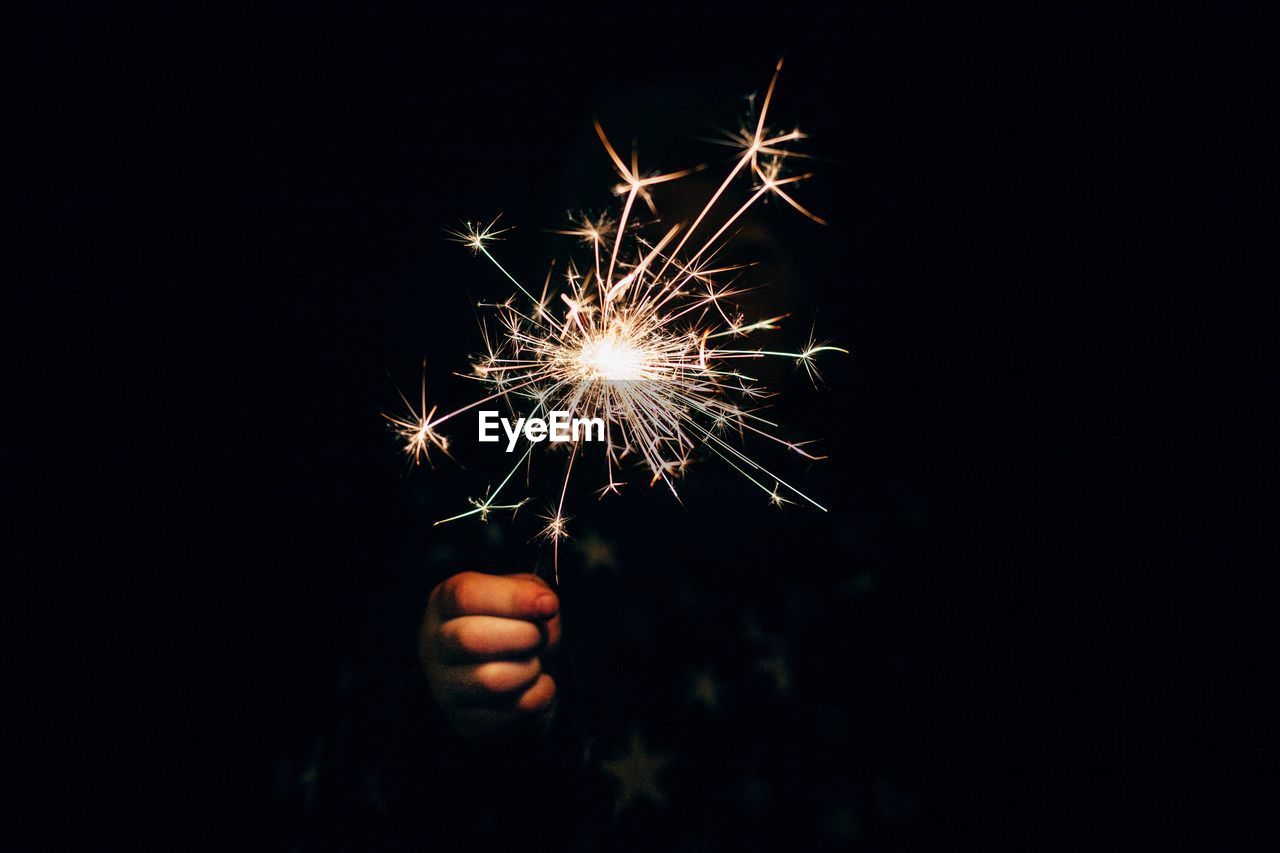 Person hand holding sparkler at night