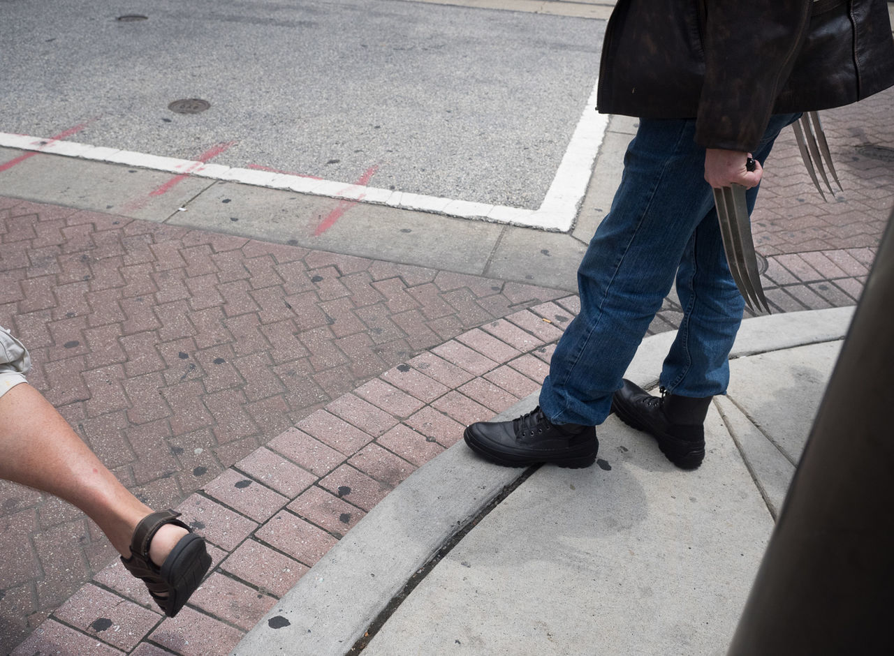 Low section of man holding weapon on sidewalk