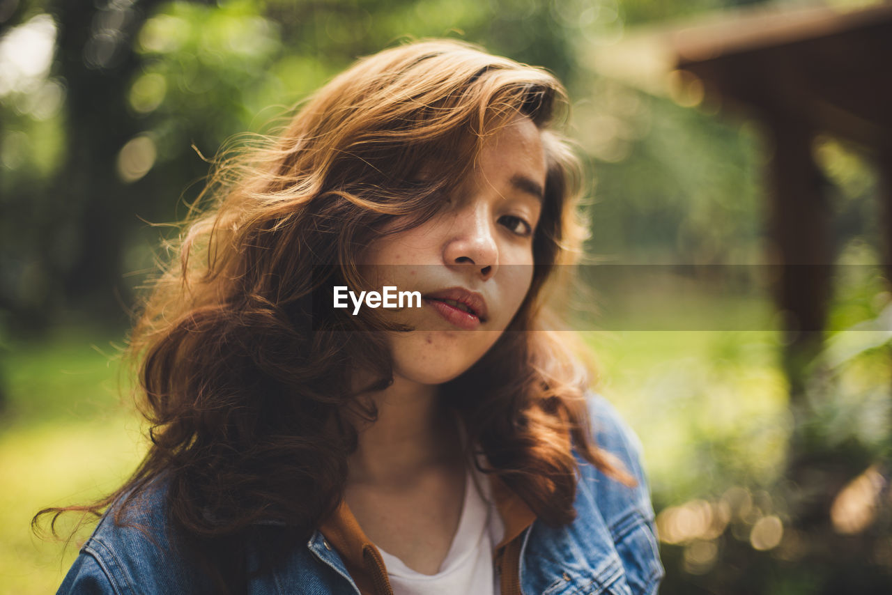 Close-up portrait of young woman standing in park