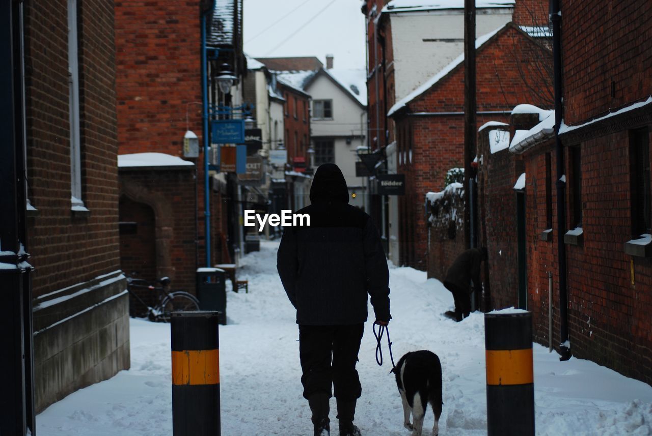 Rear view of man walking on street in city during winter