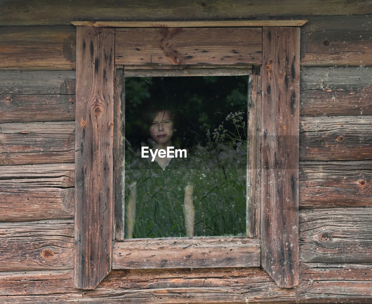 Portrait of boy looking through cottage window