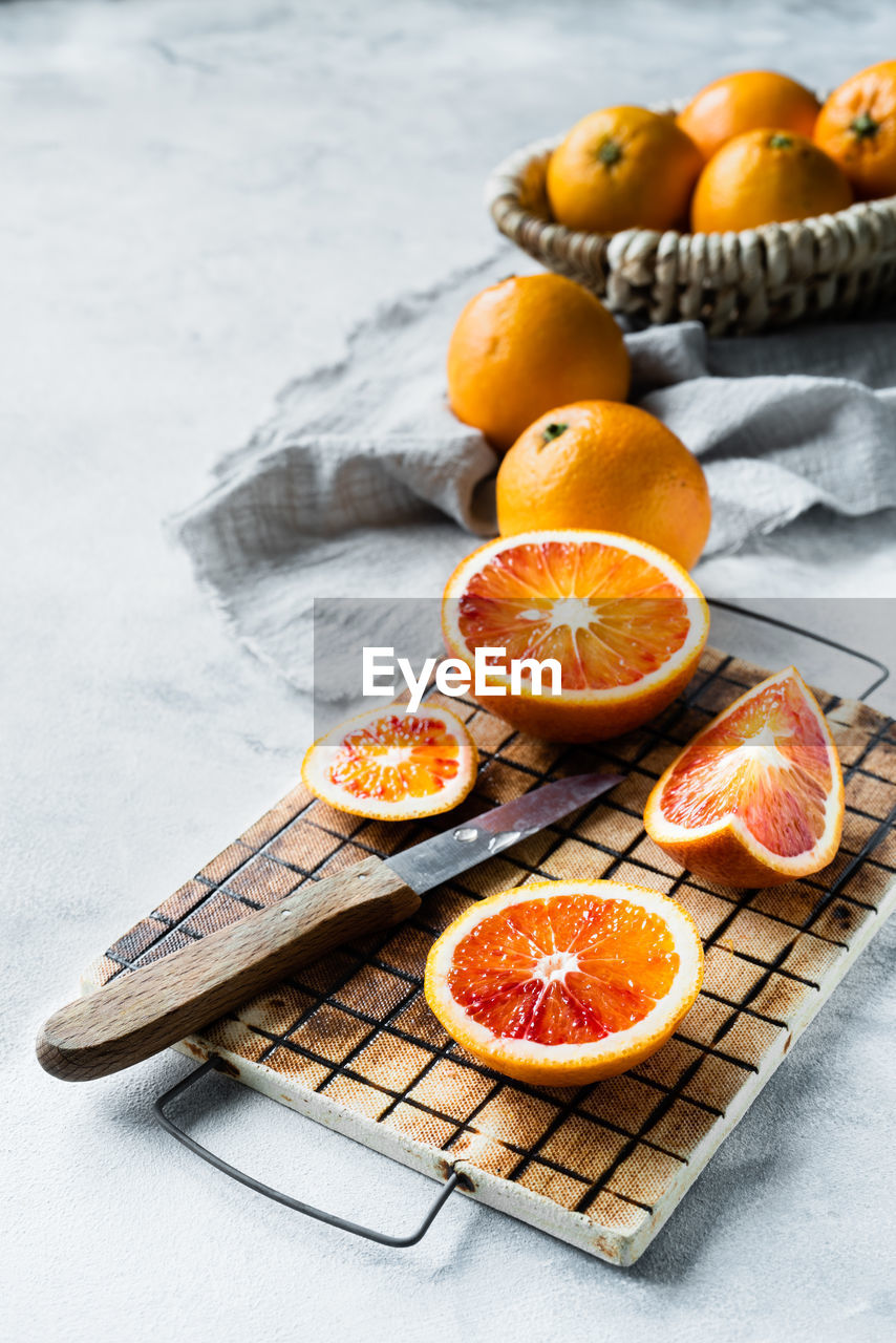 CLOSE-UP OF ORANGE FRUITS ON TABLE AGAINST THE WALL