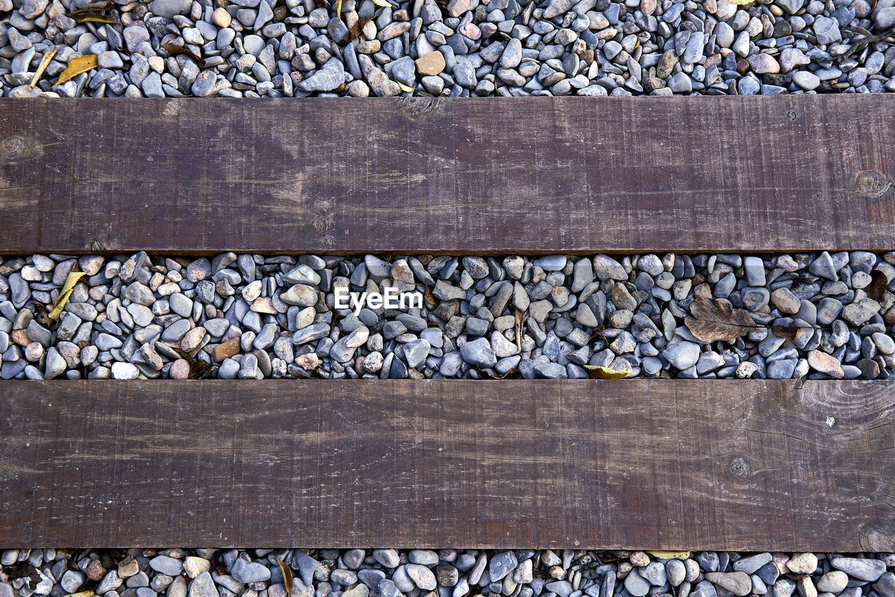 no people, day, backgrounds, full frame, pattern, stone, wall, gravel, wood, outdoors, transportation, high angle view, large group of objects, road surface, flooring, textured, abundance, railroad track, art, track, iron, nature, rock, directly above, rail transportation, architecture, metal, close-up