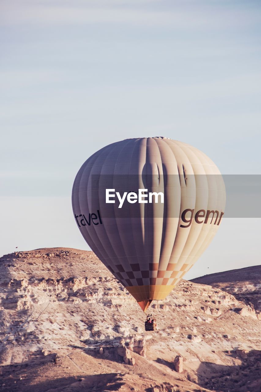 HOT AIR BALLOONS FLYING OVER MOUNTAIN AGAINST CLEAR SKY