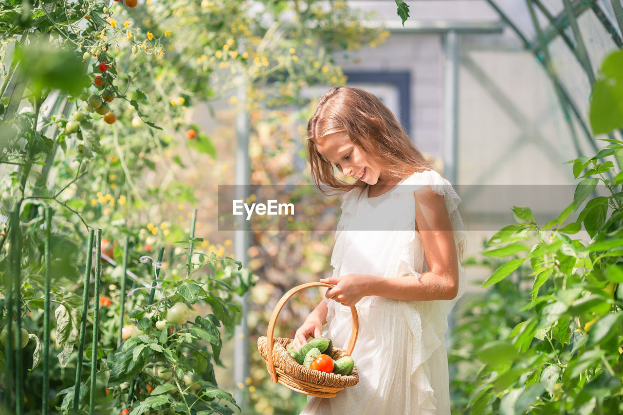 side view of young woman standing by plants