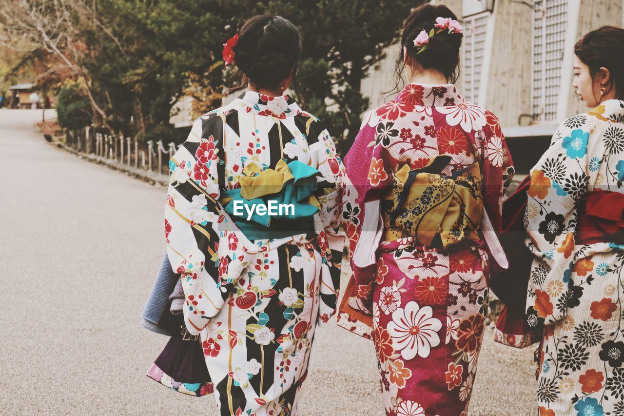 Rear view of women wearing kimonos while walking on street