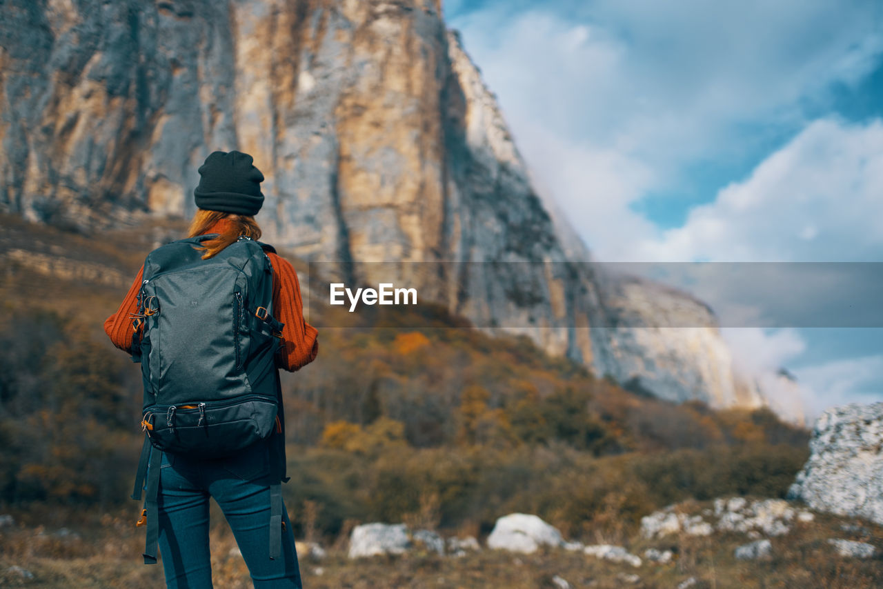 REAR VIEW OF MAN STANDING ON ROCK