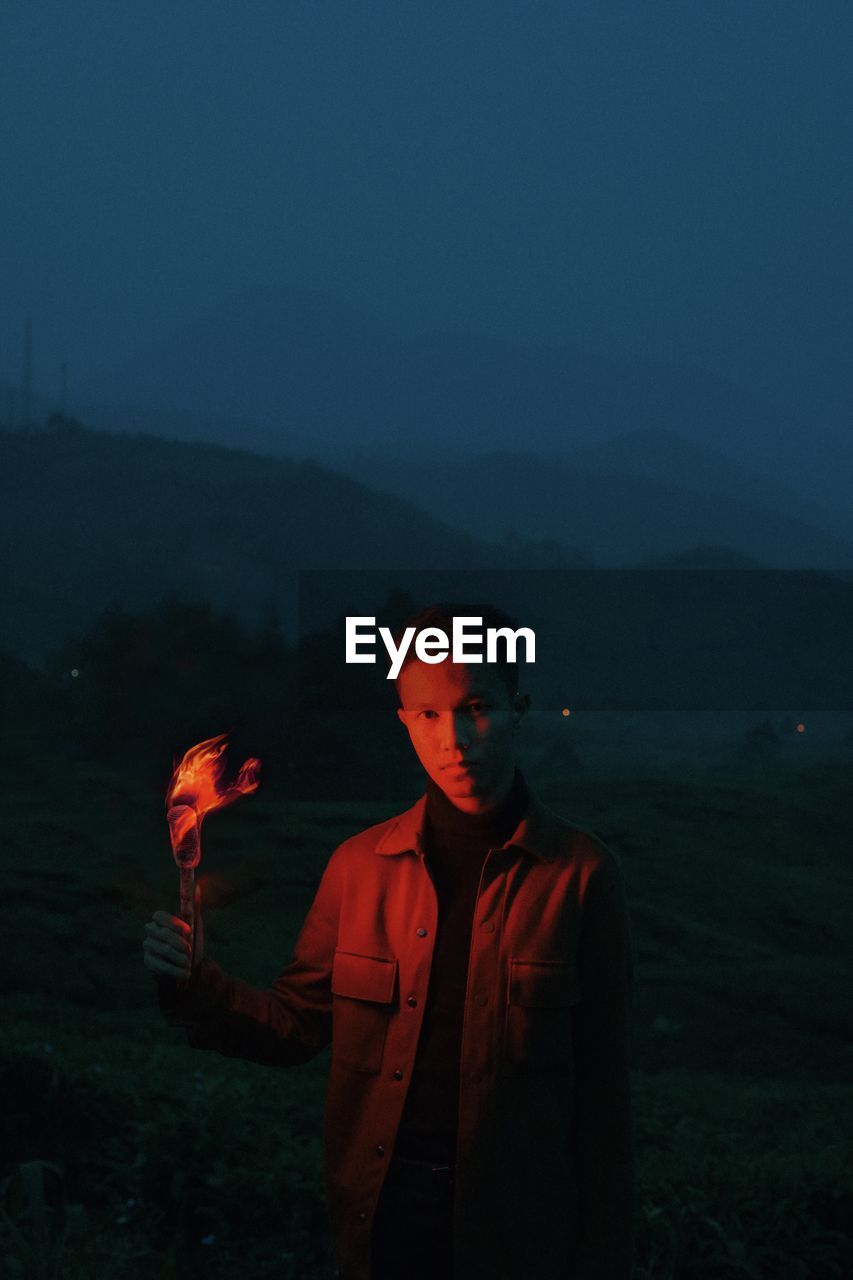 Young man standing on land against sky at night