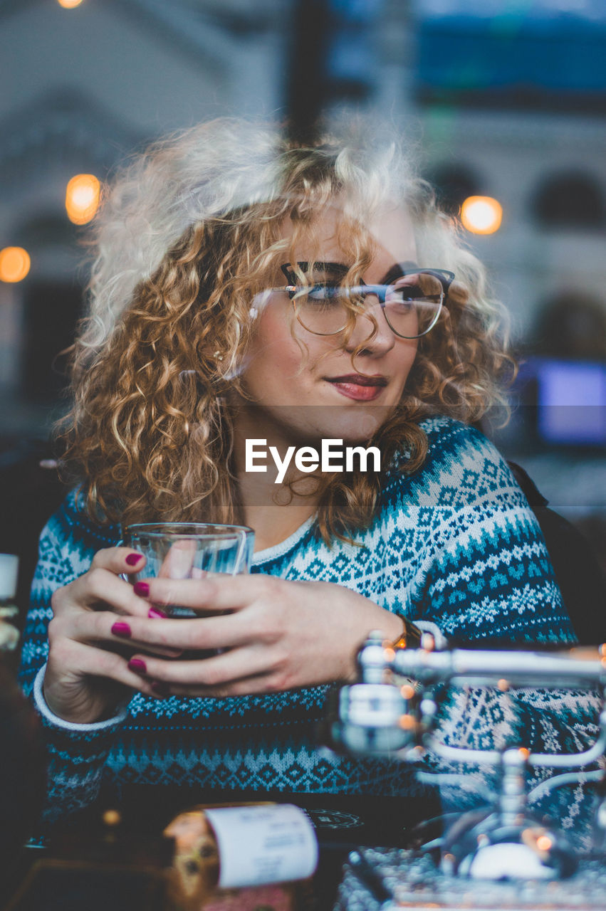 Woman having drink while sitting at table in cafe