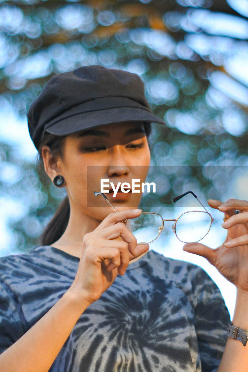 Woman with eyeglasses wearing cap at park