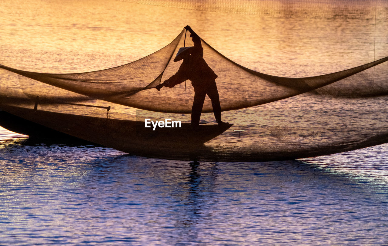 REAR VIEW OF PERSON ON BOAT AT SEA