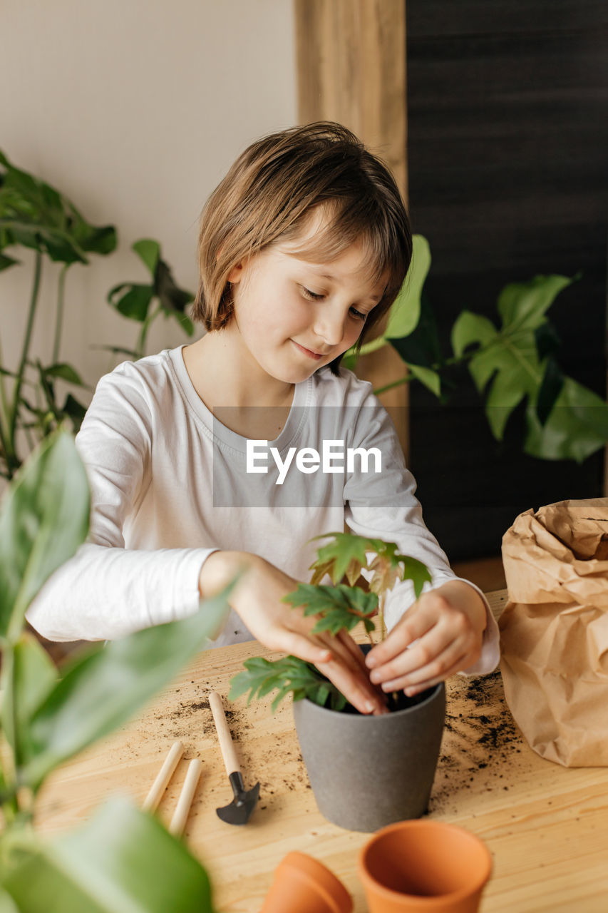 Young gardener. a cute little girl is planting or transplanting plants in a flower pot at home. 