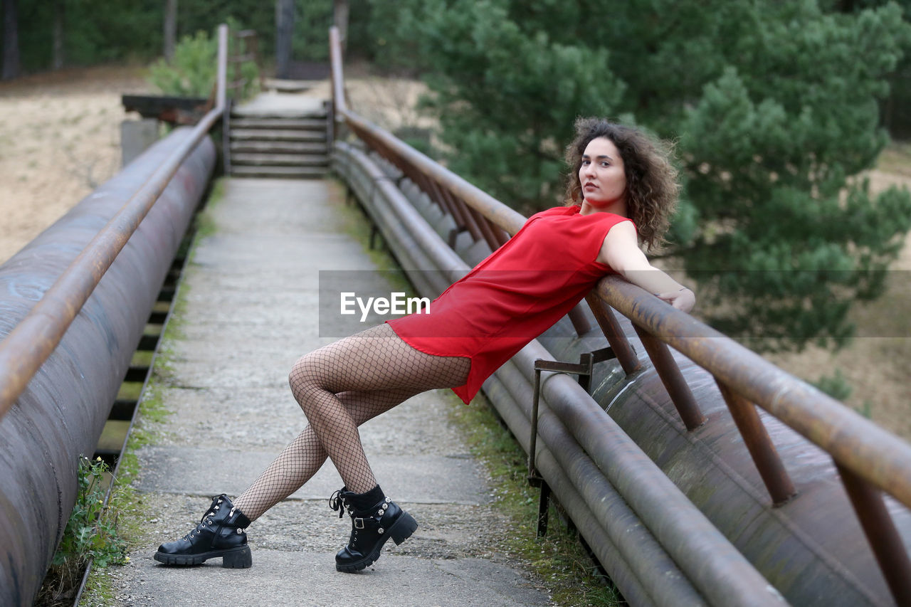 FULL LENGTH OF WOMAN ON FOOTBRIDGE AGAINST BLURRED BACKGROUND