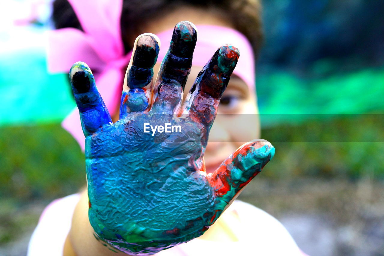 Cropped hand of girl with multi colored paint