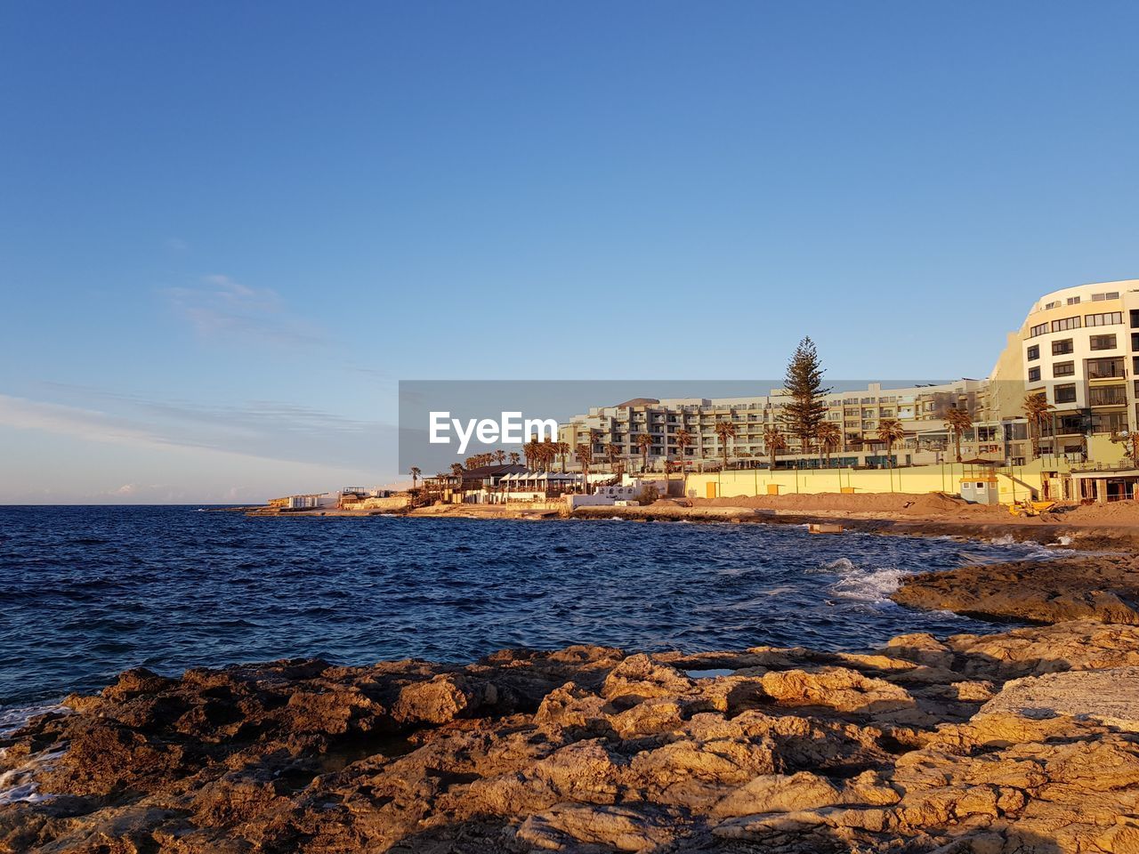 SCENIC VIEW OF SEA BY CITY BUILDINGS AGAINST SKY