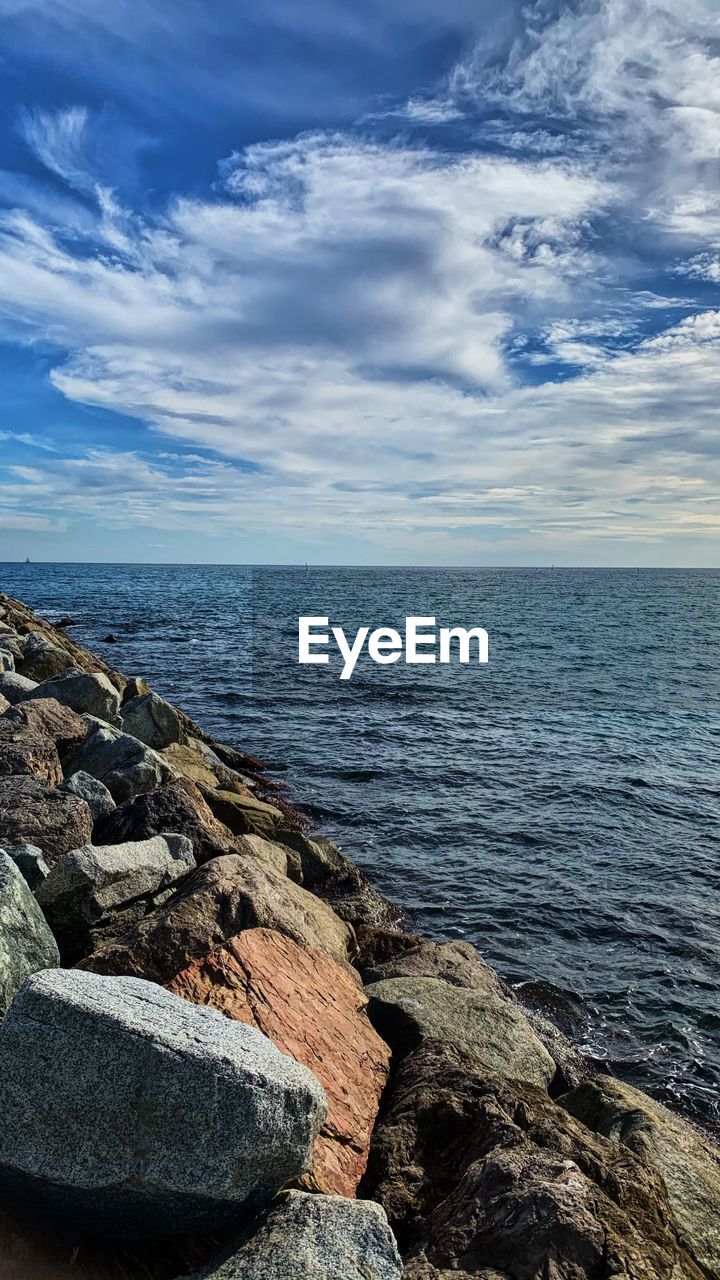 ROCKS BY SEA AGAINST SKY