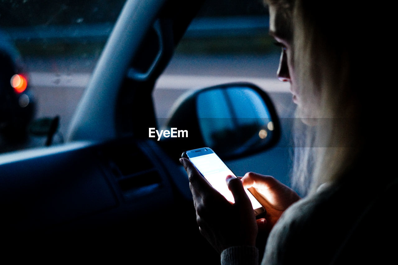 Cropped image of woman using smart phone in car