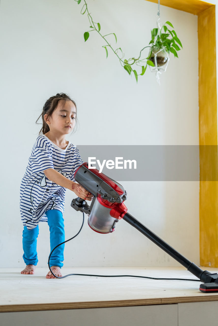 Full length of girl standing against wall at home