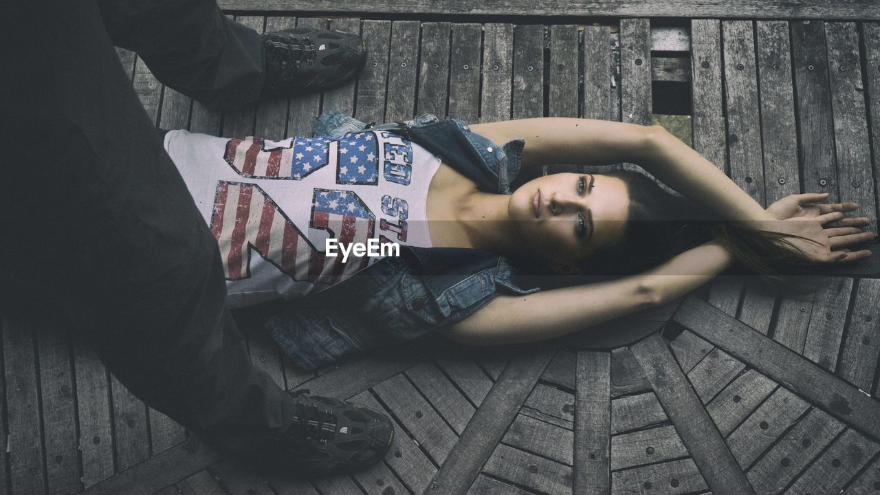 HIGH ANGLE VIEW OF YOUNG WOMAN LYING DOWN ON FLOOR