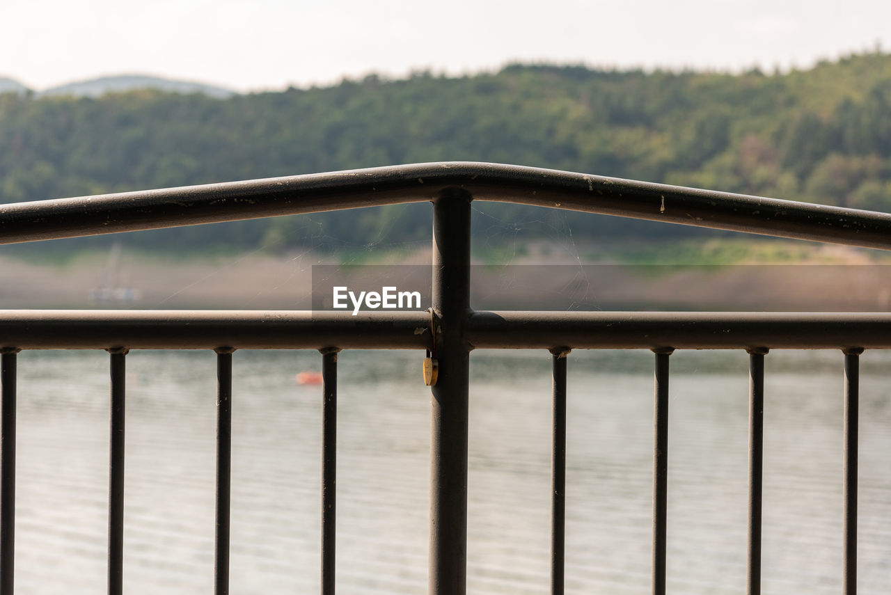 CLOSE-UP OF METAL RAILING OF RIVER DURING RAINY SEASON