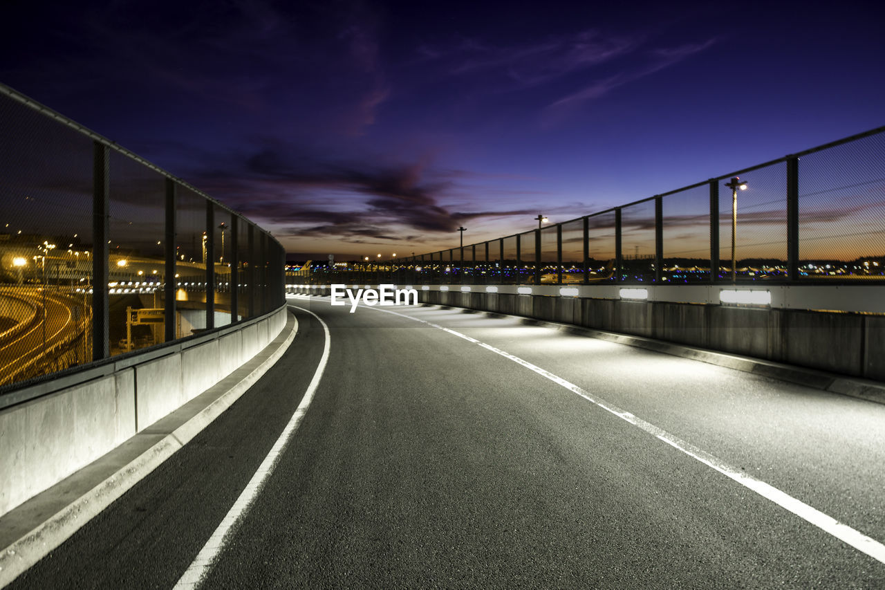 ILLUMINATED BRIDGE OVER ROAD AGAINST SKY