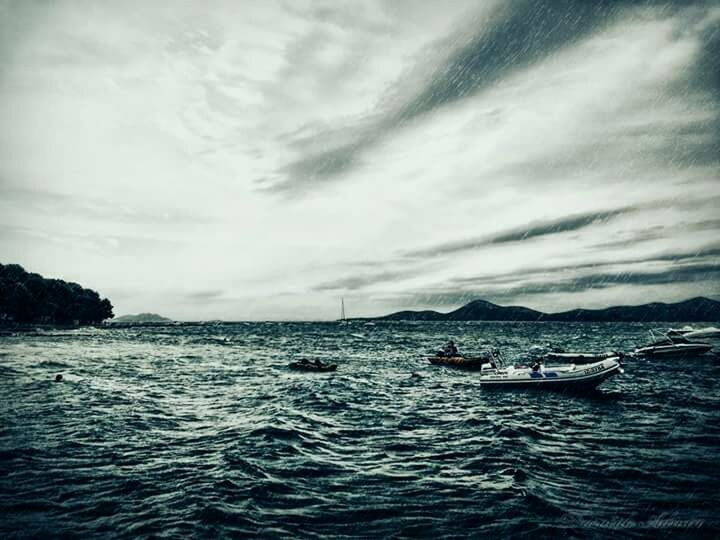 BOATS SAILING IN SEA AGAINST CLOUDY SKY