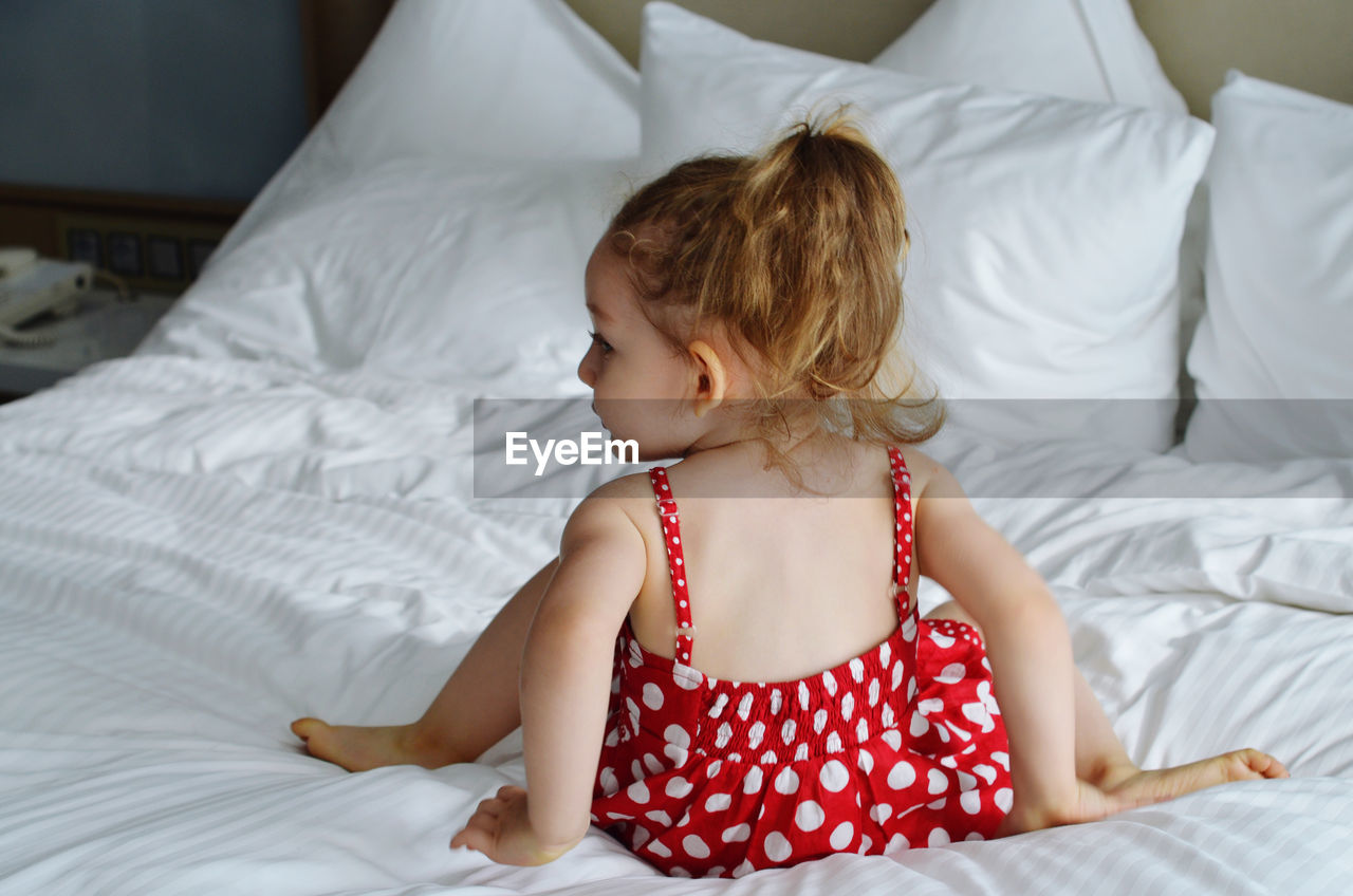 Rear view of cute girl relaxing on bed at home