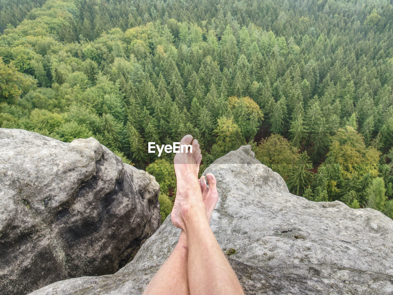 Man taking a break in nature and looking from summit down at the distant landscape.