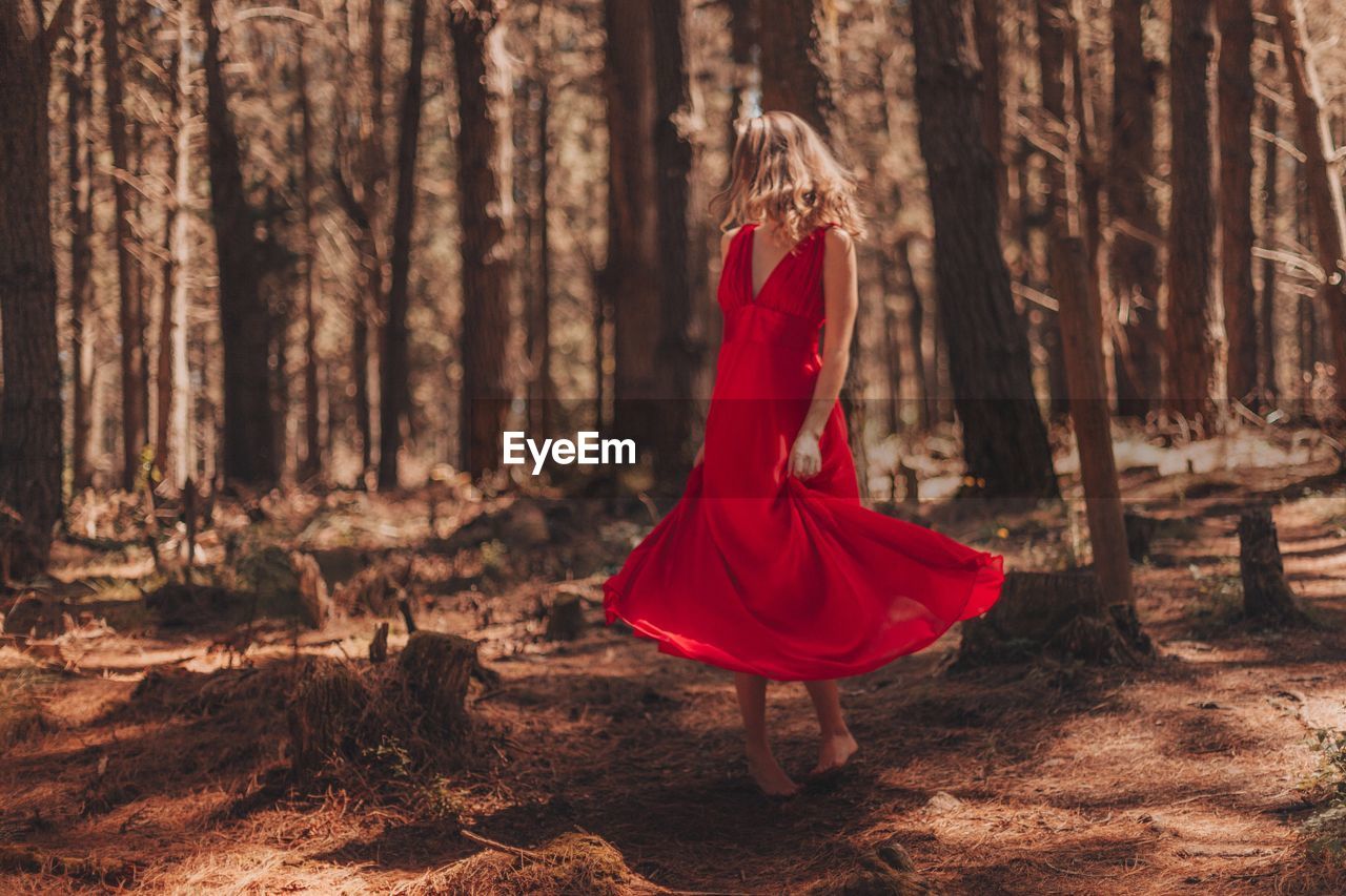 Woman in red dress standing at forest