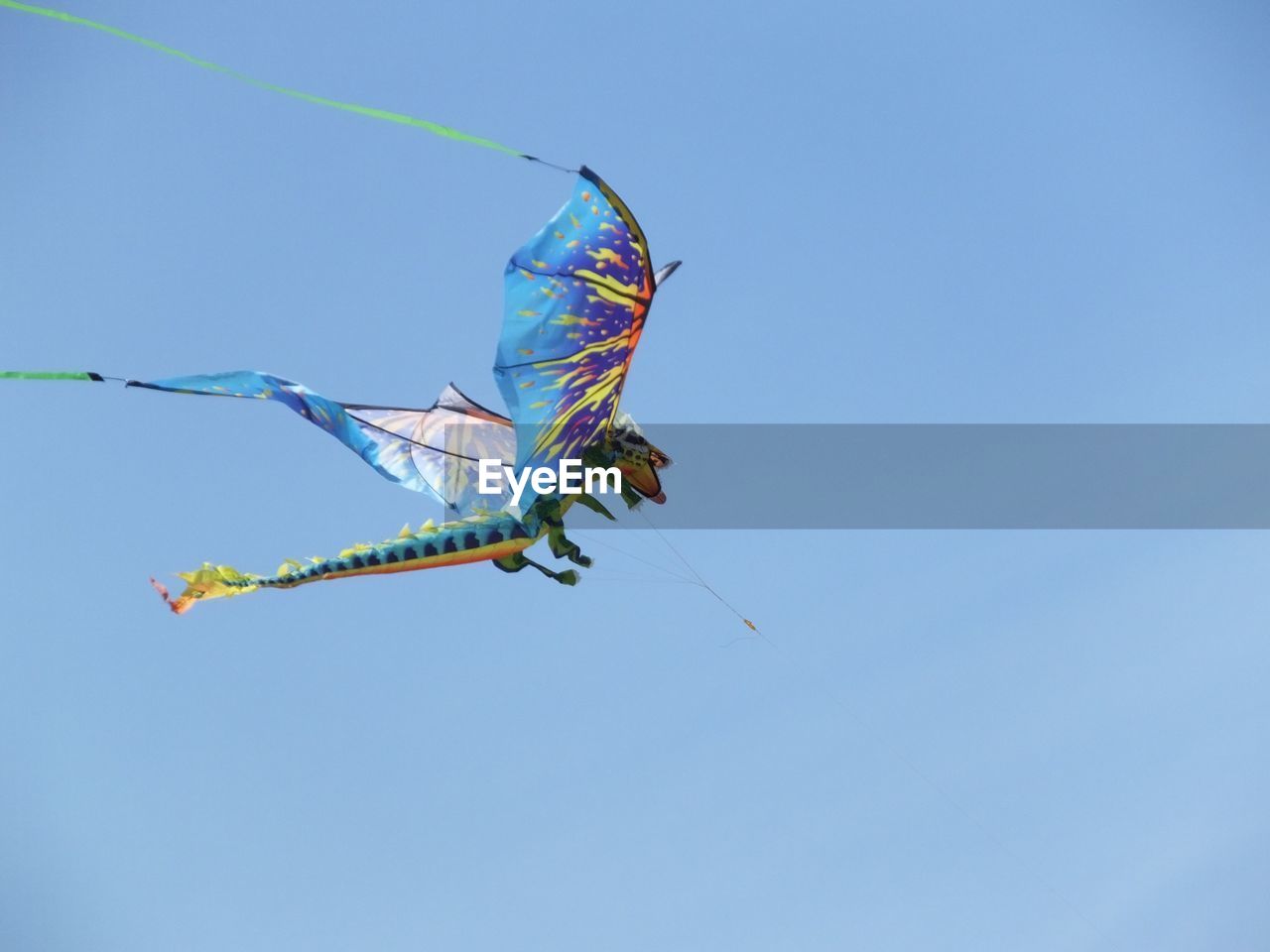 Low angle view of dragon shaped kite flying against clear sky