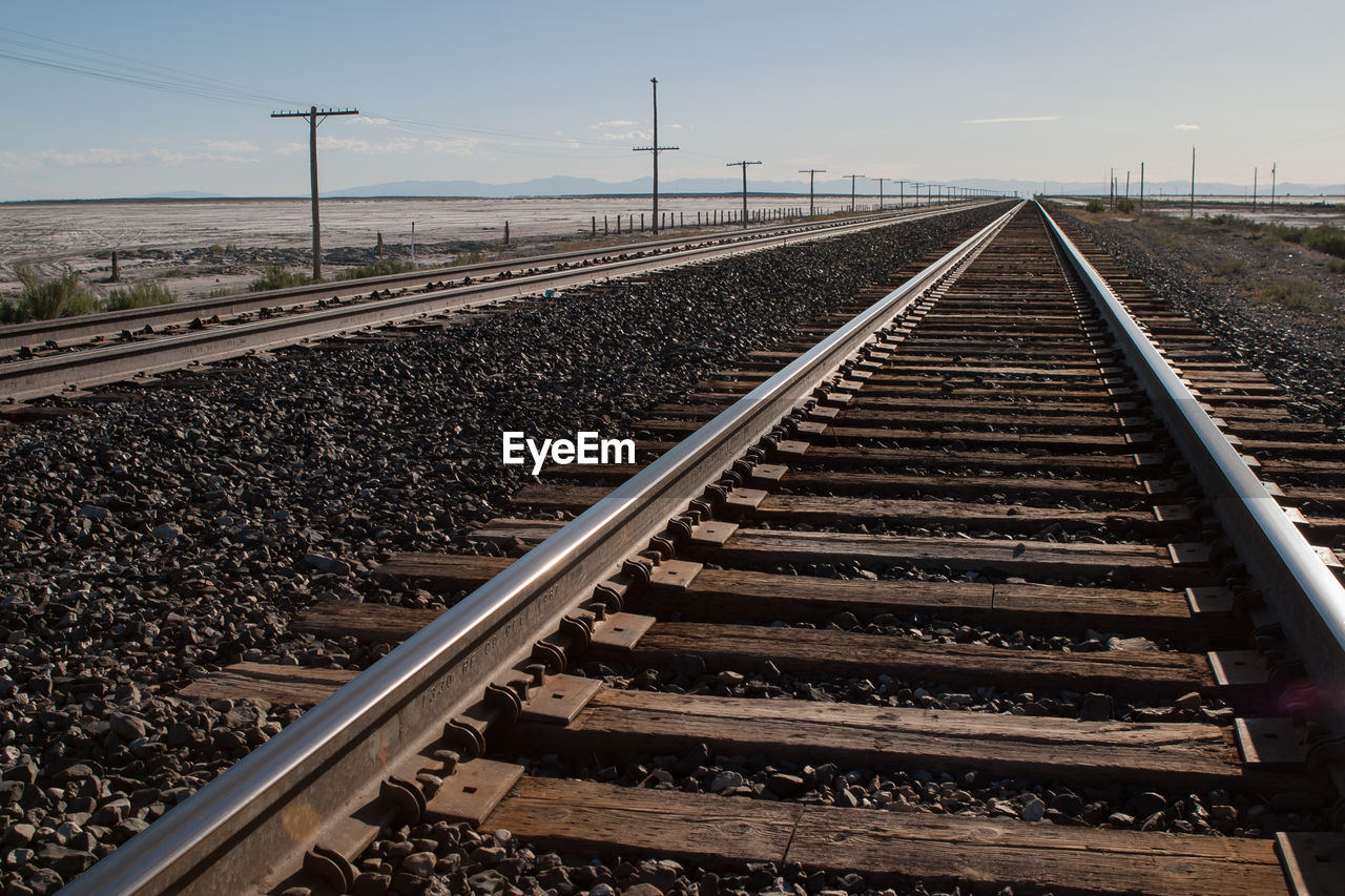 Railroad tracks by field against sky