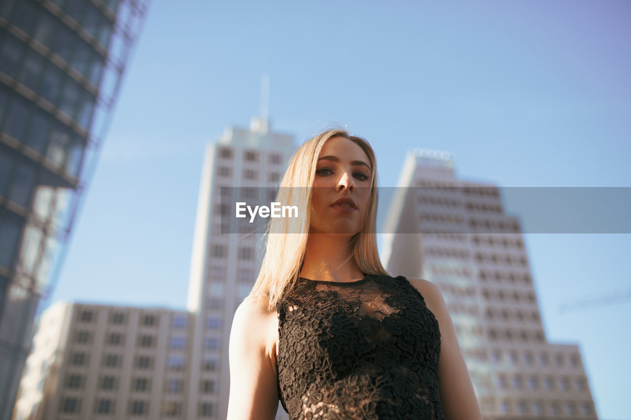 Portrait of beautiful woman standing against buildings