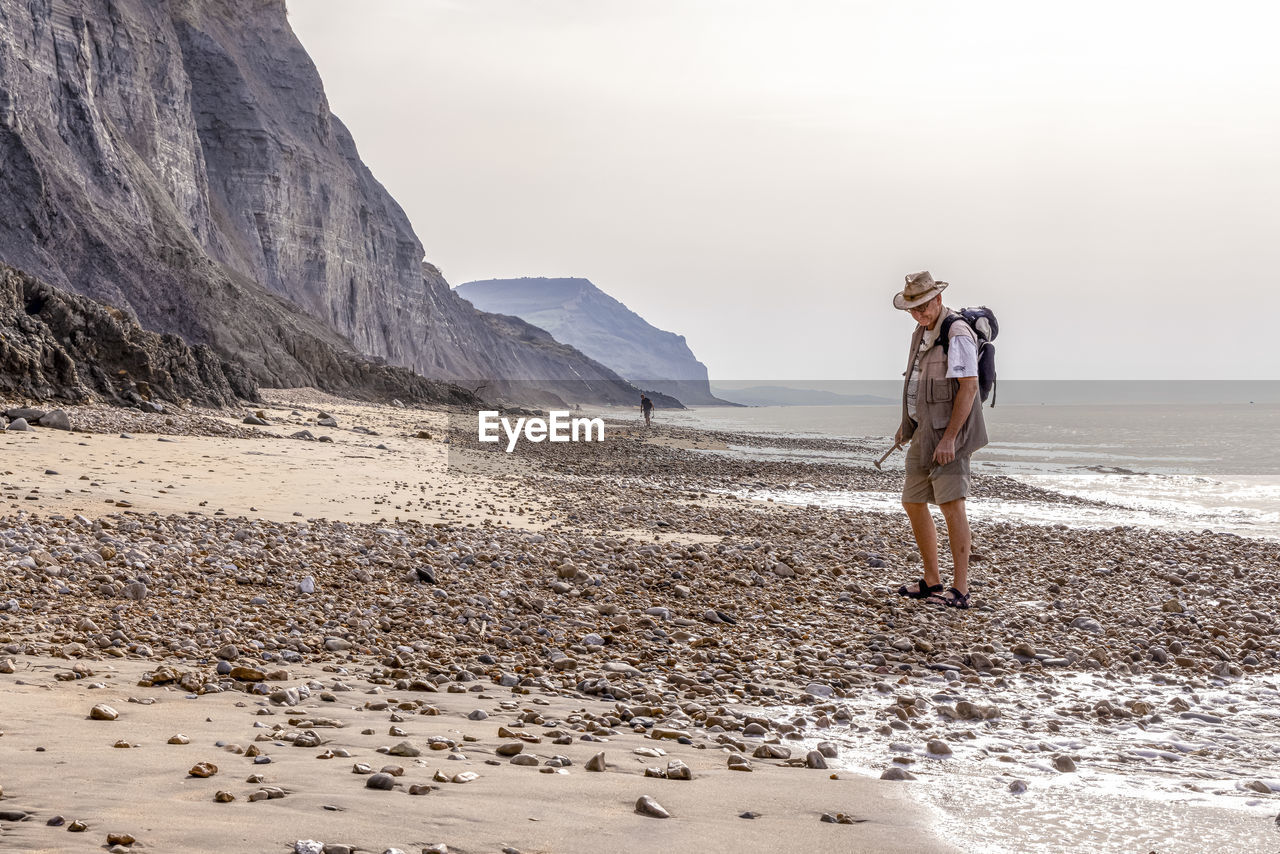 Fossil hunter on beach at charmouth in dorset, part of the jurassic coast world heritage site.