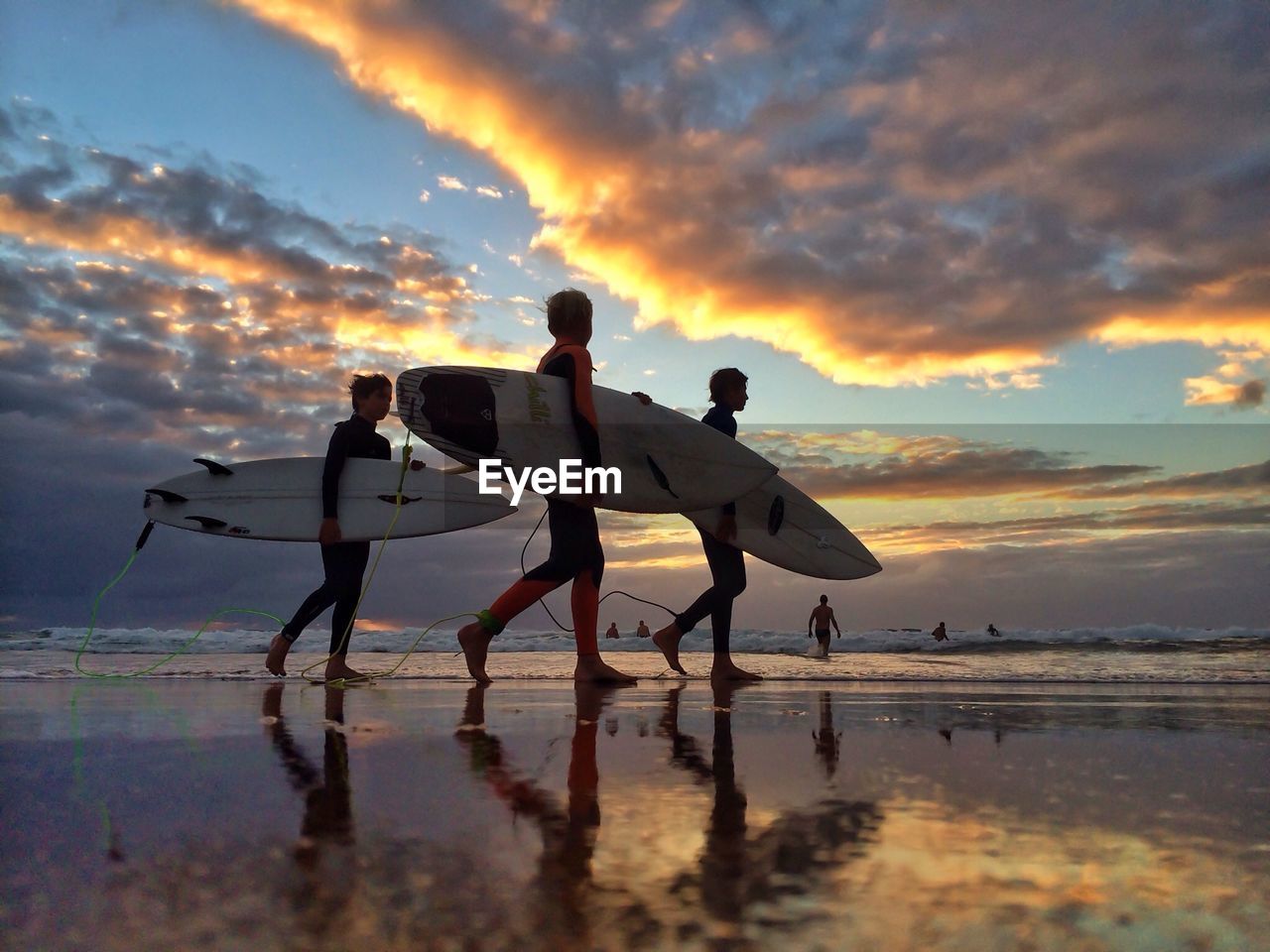 Side view of people with surfboards walking on beach