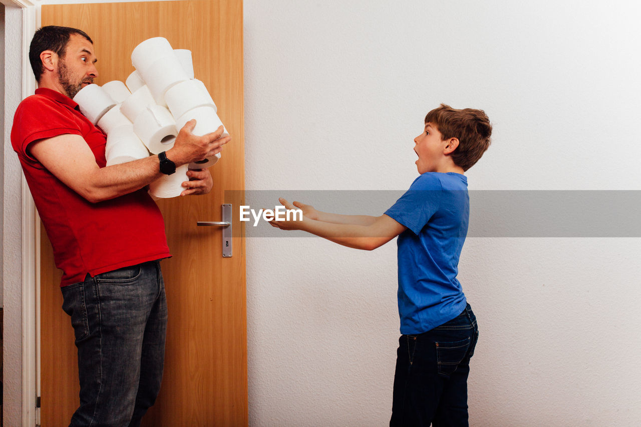 Boy looking at father carrying tissue roles