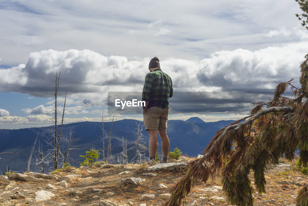 Male hiker on mountain top with dramatic clouds