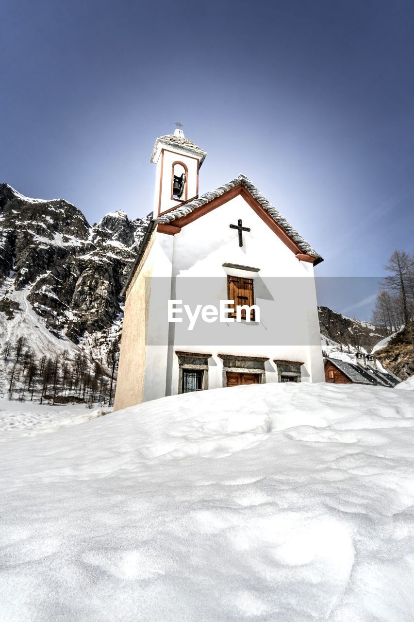 BUILT STRUCTURE BY SNOW COVERED MOUNTAINS AGAINST SKY