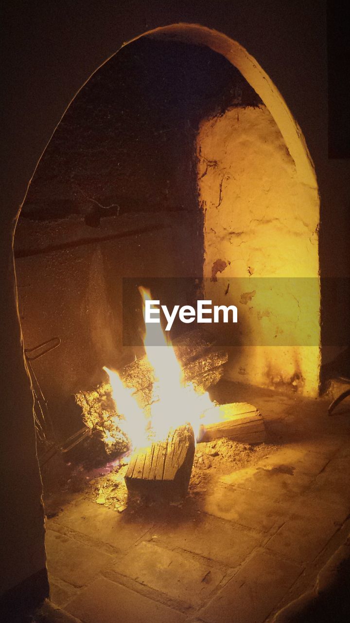 CLOSE-UP OF ILLUMINATED FIRE IN DARK ROOM