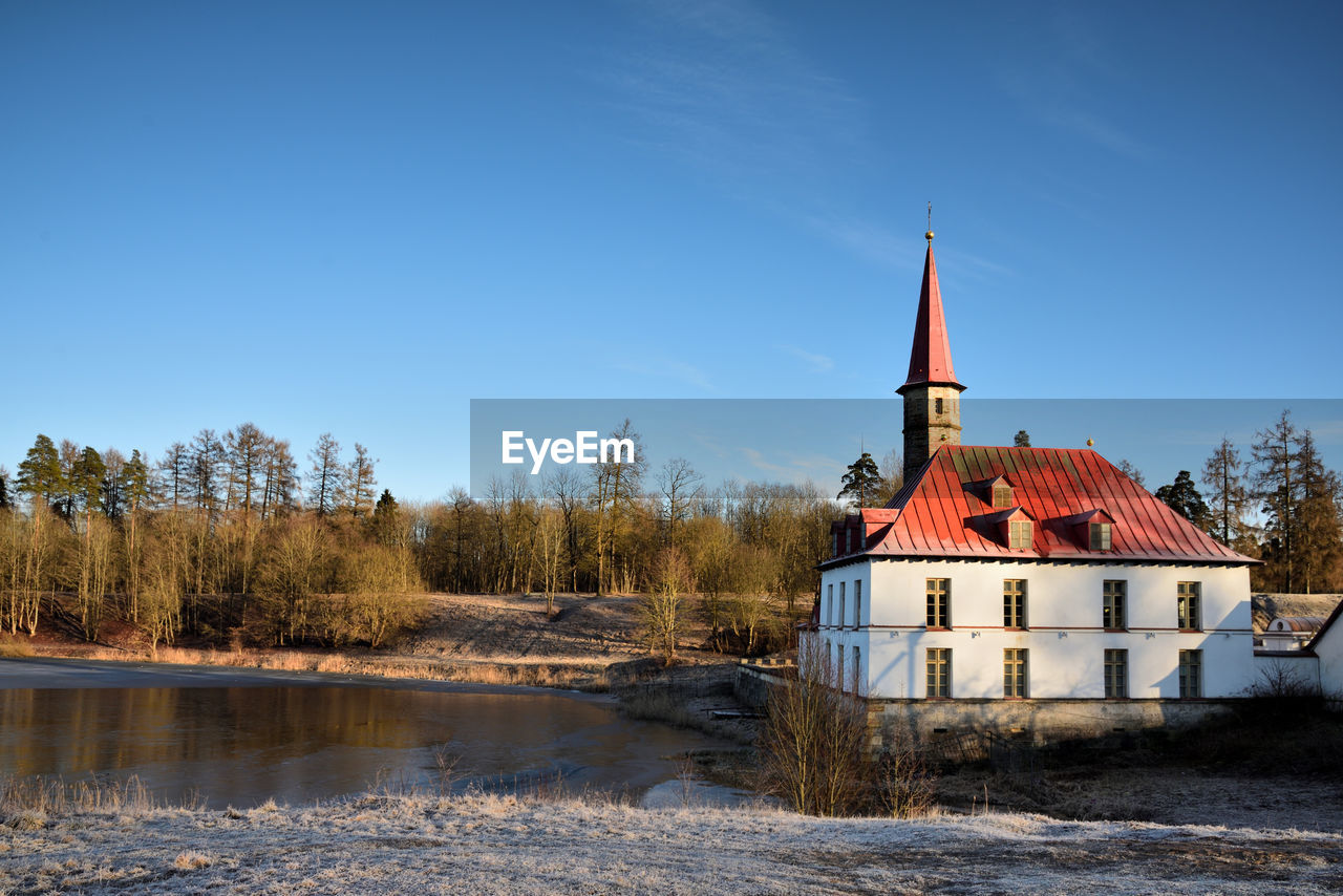 BUILDING BY RIVER AGAINST CLEAR SKY DURING WINTER