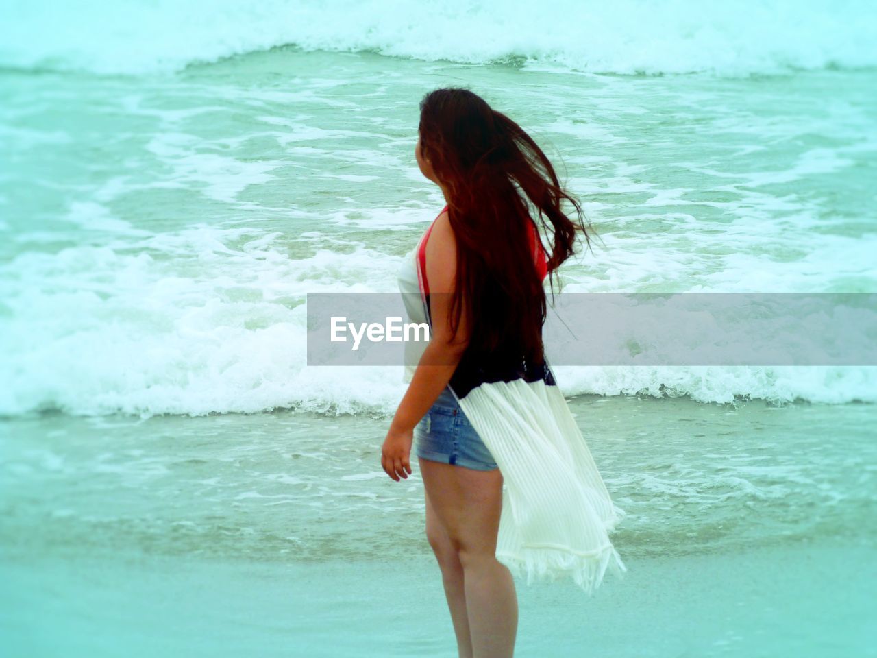 Beautiful woman standing at beach against sky