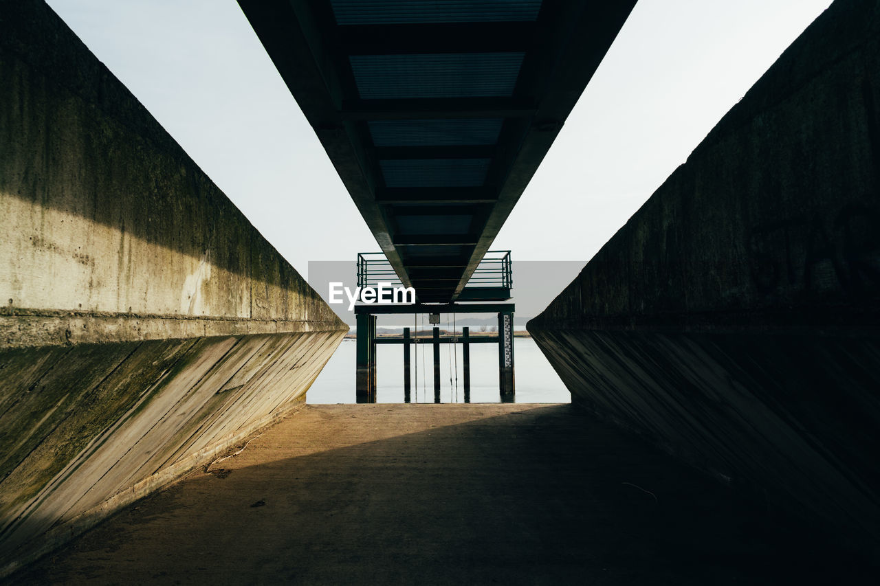 Low angle view of bridge amidst buildings against sky