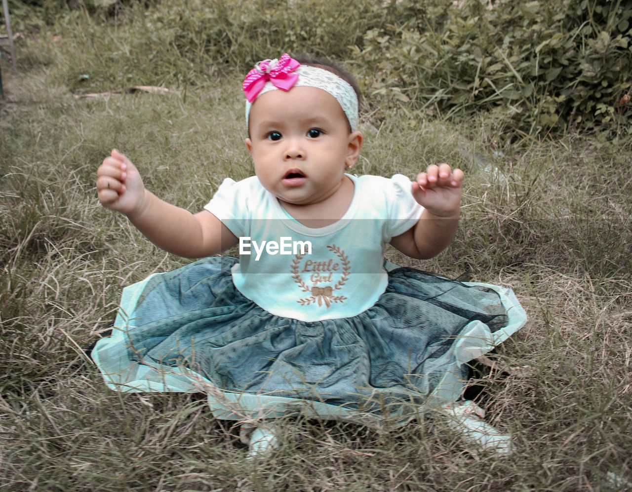 PORTRAIT OF CUTE BABY GIRL SITTING ON ROCK