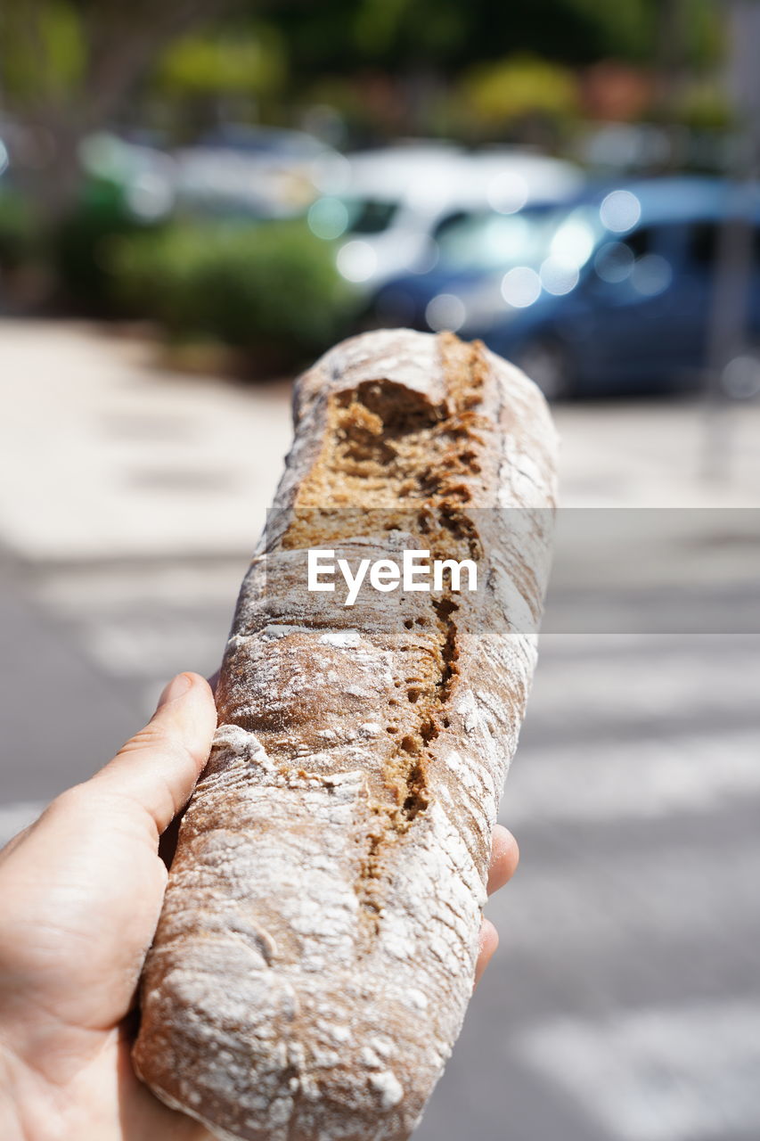 CLOSE-UP OF HAND HOLDING BREAD