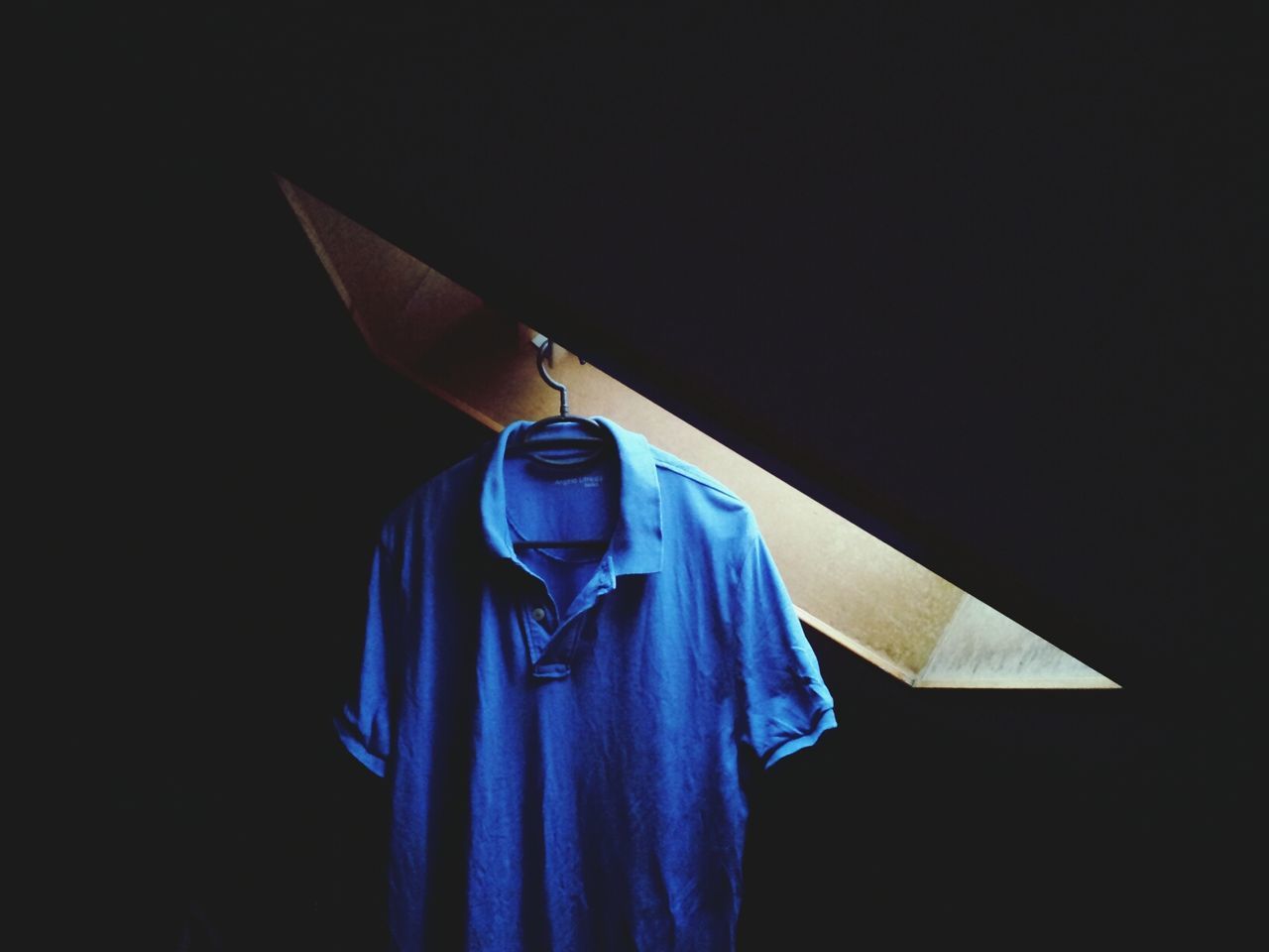 Close-up of blue shirt and hanger in the dark