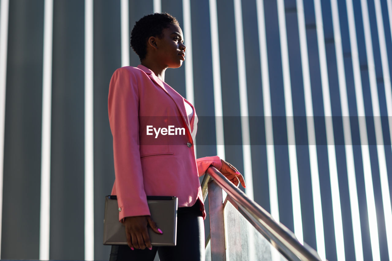 Low angle view of woman looking away while standing against railing