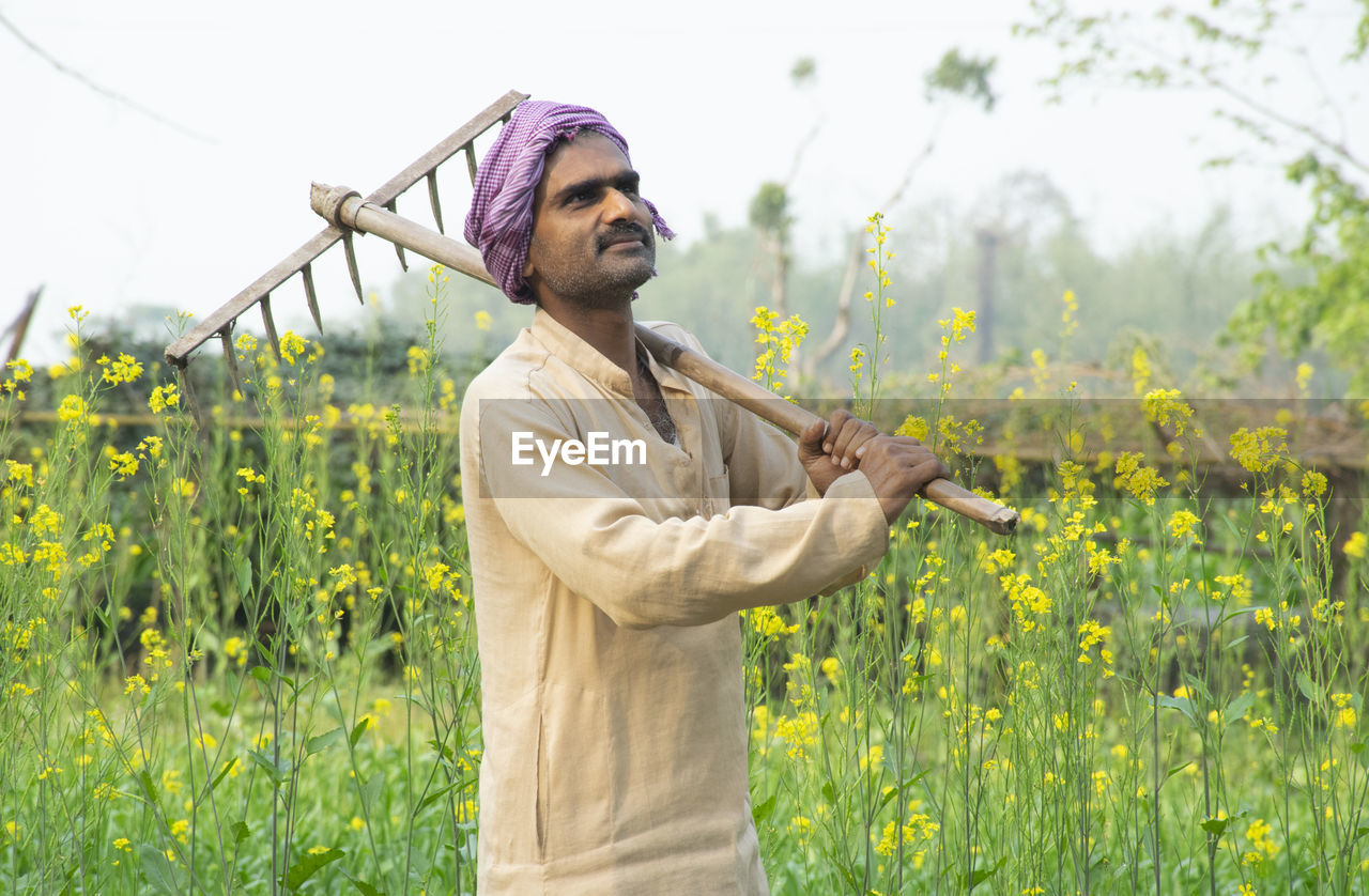 Farmer standing in field holding spade on his shoulder