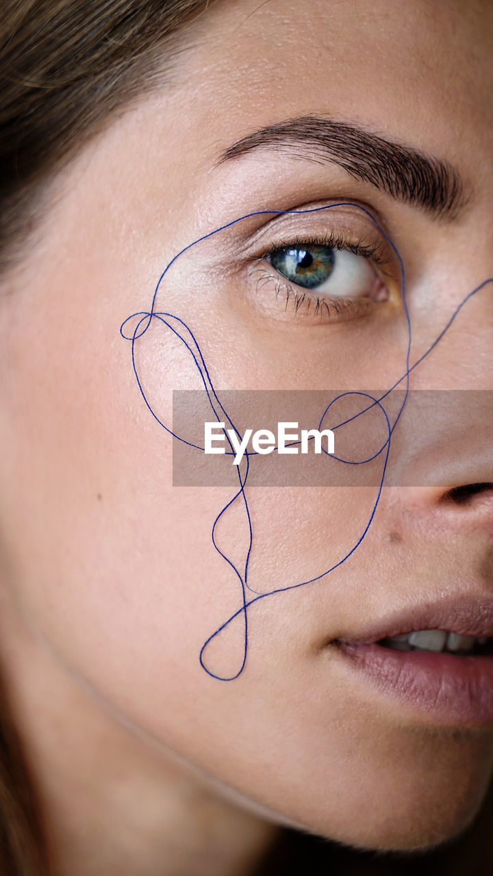 Close-up portrait of woman with thread on face