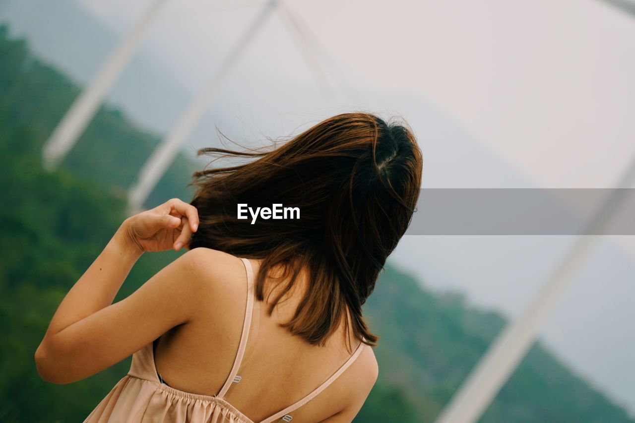 REAR VIEW OF WOMAN WITH HAIR STANDING AT CAMERA