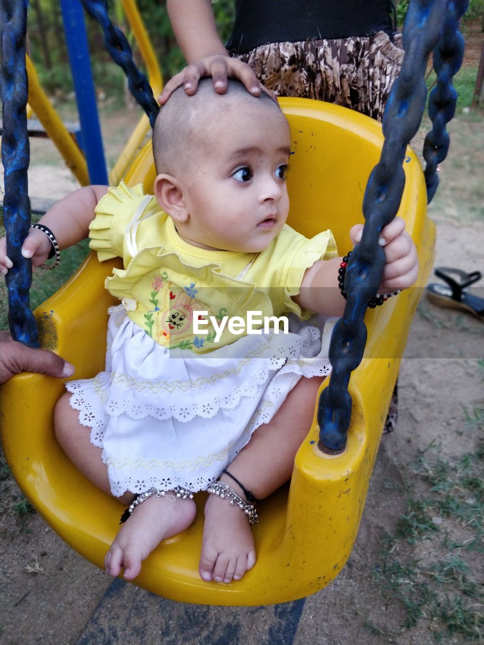 Cute girl sitting on swing in playground